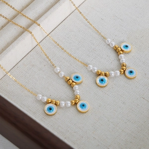 Vintage evil eye necklace with gold-plated chain and pearls on a beige jewelry tray