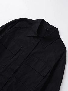 Detail of black utility shirt showing collar, chest pockets and white size S label