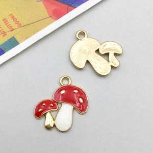 Macro view of mushroom charm showing red enamel front and golden textured back detail