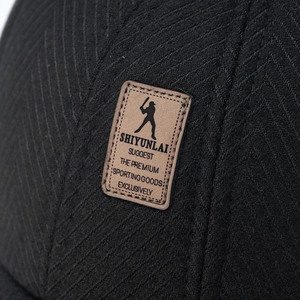 Close-up of black wool baseball cap with herringbone texture and leather brand patch