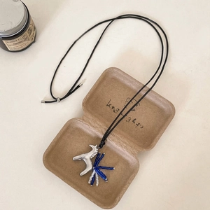 Detail of silver horseshoe pendant necklace with blue beads and tassels in a gift box