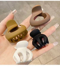 Detail view of colorful matte plastic hair clips in brown and yellow held in hand