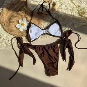 Detail of ribbed brown bikini set with shell accents and halter straps on a beach mat