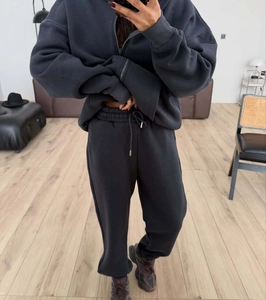 Detail of dark grey fleece tracksuit showing a zipped hoodie and drawstring joggers on model