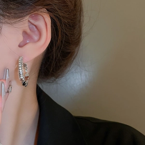 Gros plan de boucles d'oreilles doubles en argent serties de zircons sur modèle