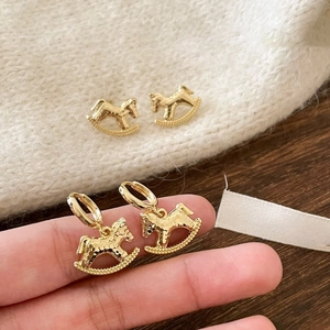 Close-up of vintage 18k gold plated rocking horse earrings with hammered metal texture