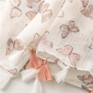 Close-up of lightweight scarf featuring pink butterfly patterns and soft handmade tassels