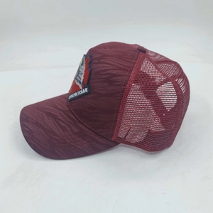 Detalle lateral de gorra trucker de malla granate con parche de águila bordado