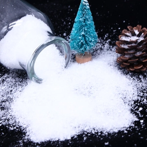 Macro shot of artificial white snow powder pouring from a glass bottle onto black surface