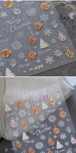 Macro detail of 3D gold Christmas nail stickers featuring snowflakes and trees