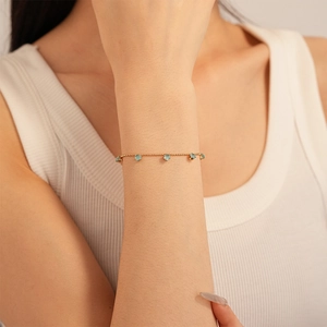 Close-up of elegant gold chain bracelet with blue zircon stones on a model's wrist