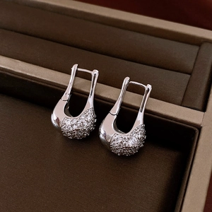 Macro detail of silver U-shaped zircon earrings with micro-pave setting on jewelry box