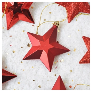 Detail of red metallic Christmas star ornament with gold string on white snowy background