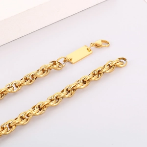 Detail of a gold braided chain bracelet with a secure lobster clasp and square metal tag