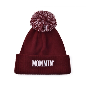 Detail of burgundy ribbed knit beanie with MOMMIN embroidery and pom-pom topper