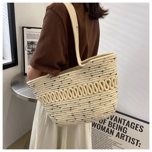 Detailed view of beige woven tote bag with black wavy stripes and thick shoulder strap