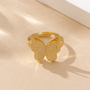 Close-up of golden butterfly ring featuring textured matte wings and open adjustable band