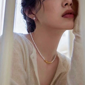 Detail of s925 silver necklace with white freshwater pearls and golden accent beads
