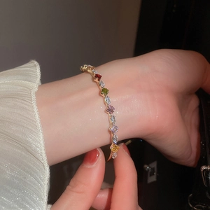 Macro detail of gold-plated bracelet featuring vibrant multi-colored zircon stones