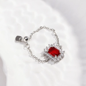 Detail of adjustable chain ring with red square gemstone and heart pendant charm