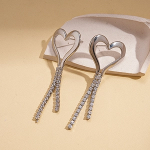 Close-up of silver hollow heart earrings with sparkling zircon tassels on a tray