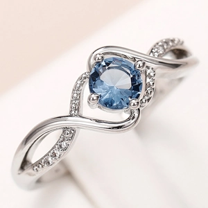 Elegant wavy silver ring featuring a round blue gemstone and pavé zircon accents