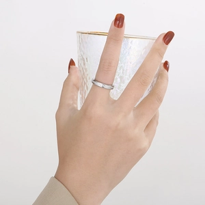 Elegant silver eternity ring with sparkling stones worn on a hand holding glassware