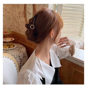 Detail of a dark tortoiseshell hair claw with gold ring accent on an elegant updo hairstyle