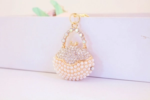 Close-up of golden handbag keychain with white pearls and sparkling rhinestones