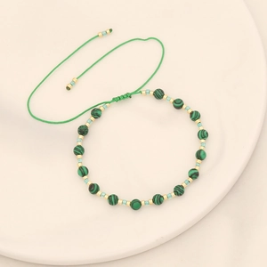 Détail d'un bracelet tissé en perles avec pierres malachites vertes et perles dorées