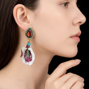 Vintage flower tassel earrings with red teardrop gem and enamel lily on a model