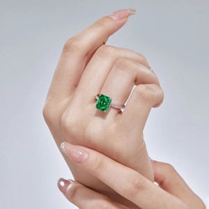 Close-up of an S925 silver ring featuring a large emerald cut green gemstone on a model hand