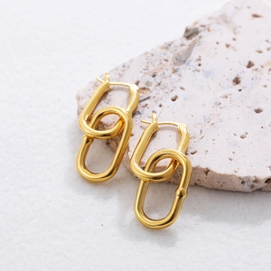 Macro shot of gold-plated stainless steel U-shaped chain earrings on white stone