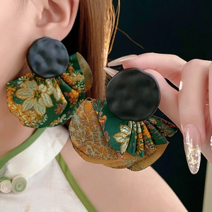 Close-up of retro black and green fabric fan-shaped drop earrings worn by a model