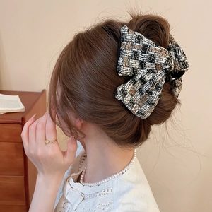 Détail de la pince à cheveux en tweed montrant la texture tissée et le design élégant