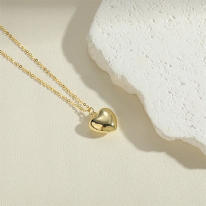 Polished heart pendant necklace in golden finish on a textured white stone background