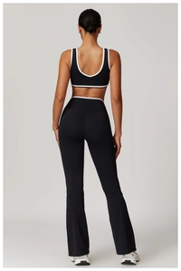 Rear view of black flare yoga set featuring contrast piping and a deep U-neck back design
