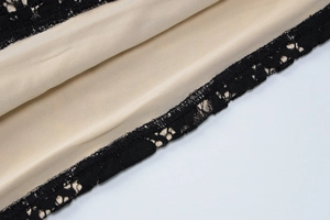 Gros plan sur la dentelle noire élégante et la doublure en satin beige d'une robe de soirée