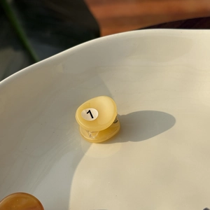 Mini yellow acetic acid hair claw with number 1 billiard style design in ceramic dish