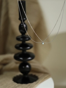 Close-up of minimalist silver necklace featuring a round blue opal pendant on fine chain