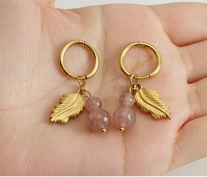 Detailed macro view of 18K gold-plated leaf earrings with translucent strawberry quartz beads
