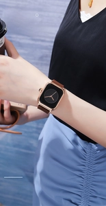 Detail of rose gold square watch with black dial and brown leather strap on wrist