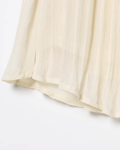 Détail de l'ourlet de la jupe midi beige montrant la texture plissée et les coutures