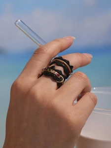 Ensemble de bagues noires ondulées avec pierres colorées et anneau d'or sur la main