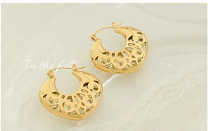 Détail macro de boucles d'oreilles cœur ajouré doré sur dentelle au design rétro vintage