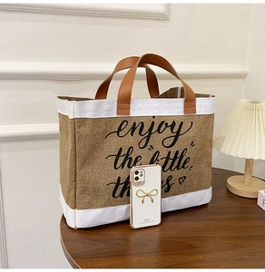 Detailed shot of burlap tote bag with leather handles and enjoy the little things text
