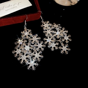 Macro shot of silver snowflake earrings with shiny rhinestones on a dark background
