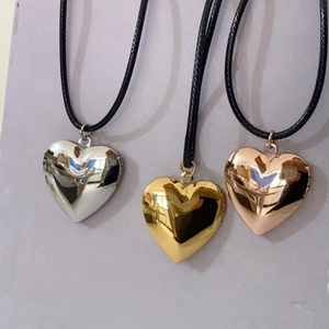 Three polished heart-shaped floating lockets in silver, gold, and rose gold with black cords