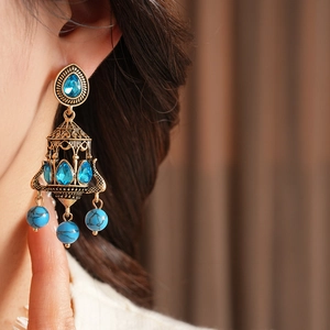 Close-up of vintage chandelier earring with sky blue stones and intricate bronze metalwork