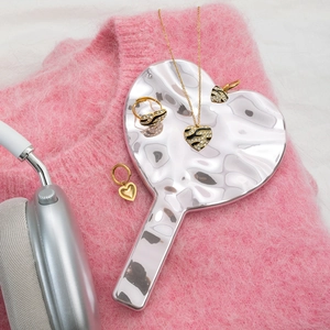 Detail of gold heart jewelry set with black enamel and zircons on a silver tray
